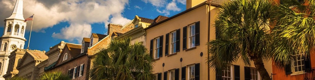 A white church steeple and row of townhouses and palm trees in Charleston South Carolina, the host of the hyperbaric oxygen therapy conference, HBOT